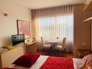 a bedroom with a bed and a table with a television at Free Wave Rooms in Maia