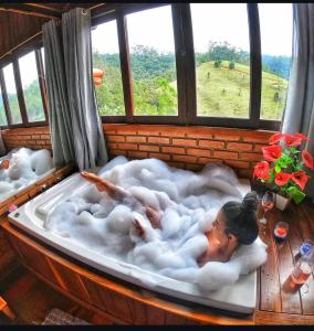 eine Frau, die in einer Badewanne in einem Zimmer liegt in der Unterkunft Paraíso da serra visconde de Mauá in Visconde De Maua