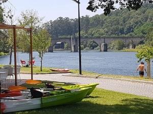 a green boat sitting on the grass next to a river at Casa acolhedora in Ponte da Barca