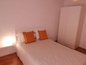 a bedroom with a white bed with two orange pillows at Casa acolhedora in Ponte da Barca