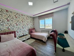 a bedroom with two beds and a table and a window at RÉSIDENCE LA TERRASSE s2 AVEC BALCON & TERRASSE "Only Family" in Hammamet +12 photos