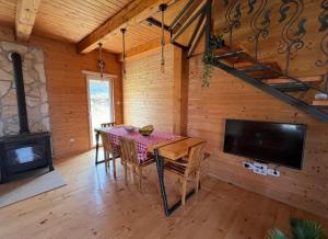 a dining room with a table and a tv and a fireplace at Mountain Peace Cottage in Žabljak