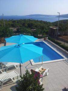 a blue umbrella and chairs next to a swimming pool at Apartment Milat in Seget Donji