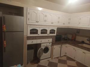 a kitchen with white cabinets and a refrigerator at Mogadorista pour les familles in Essaouira