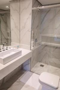 een witte badkamer met een wastafel en een toilet bij Apto Studio Hotel Praia Brava in Florianópolis
