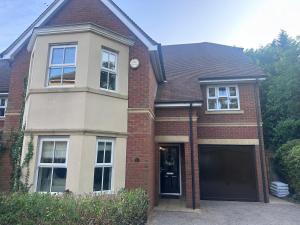 ein rotes Backsteinhaus mit einer schwarzen Garage in der Unterkunft Elegant 5 Bed 5 Bath Home in Englefield Green