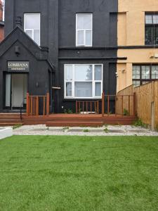 a black house with a wooden fence and a yard at Deluxe 2BR Apartment Near City Center - Sleeps 6 in Liverpool