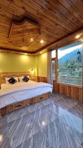 a bedroom with a large bed and a large window at deja view orchard, old manali in Manāli
