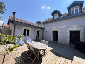 eine Terrasse mit Tisch und Stühlen auf einem Deck in der Unterkunft Résidence 191-soulac Sur Mer - 191 - Villa Soulacaise de charme au cœur de Soulac-sur-Mer MAE-9123 in Soulac-sur-Mer
