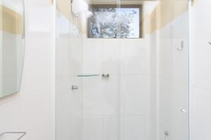 a white bathroom with a shower with a window at Casa Santa Cruz in Passo Fundo +22 photos