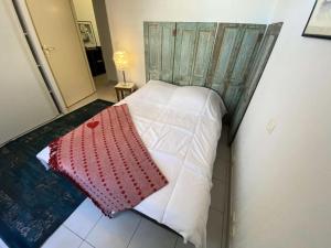 un piccolo letto con un cuscino rosso e bianco di Résidence Les Vagues - 156 - Appartement en rez de jardin résidence Les Vagues MAE-7381 a Soulac-sur-Mer