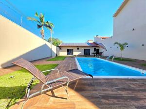 a patio with two chairs and a swimming pool at 2 Suítes Novas Alto padrão Área de Lazer Ampla in Foz do Iguaçu