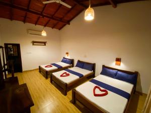 a room with two beds with red accents on them at Oasis Bay - Arugam Bay in Arugam Bay