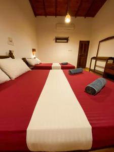 a bedroom with two beds with red and white blanket at Oasis Bay - Arugam Bay in Arugam Bay