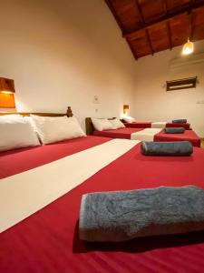 a room with four beds with red and white blankets at Oasis Bay - Arugam Bay in Arugam Bay