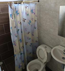 a bathroom with a toilet and a shower curtain at Hotel Y Piscina Malecón in Acacías