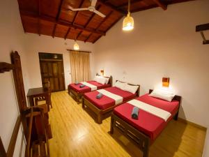 three beds in a room with wooden floors at Oasis Bay - Arugam Bay in Arugam Bay