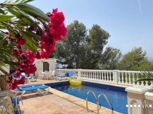 a swimming pool with a white fence and red flowers at VH CostaBlanca - RULLE in Benissa