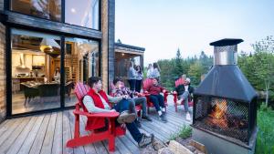 a group of people sitting on a deck with a fireplace at Le Baluchon Éco-villégiature in Saint-Paulin