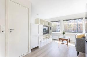 a white living room with a tv and a table at Modern apartment ONLY 5 minutes from City centre in Bergen