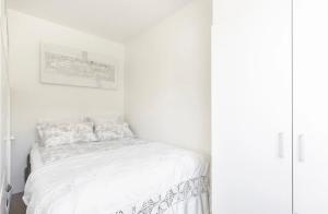 a white bedroom with a bed with white sheets at Modern apartment ONLY 5 minutes from City centre in Bergen