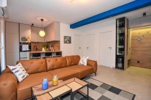 帕格Apartment T E A Pag的一间带棕色沙发的客厅和一间厨房