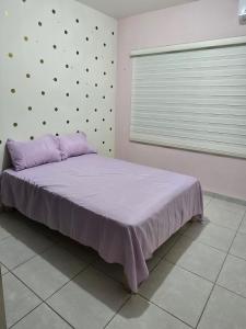 a bedroom with a bed with purple sheets and a window at Pozos Comfort House in San Luis Potosí