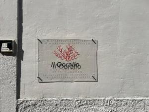 a sign on the side of a white wall at Il Corallo in Terracina