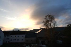 ein Sonnenuntergang über einer Stadt mit Gebäuden und einem Baum in der Unterkunft Hotel zum Müller in Lichtenfels