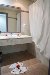 un bagno con un lavandino e un asciugamano con fiori sul pavimento di Hôtel Excel KHIMA a Yasmine