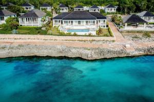 an aerial view of a house with blue water at French Leave Resort, Autograph Collection in Governorʼs Harbour