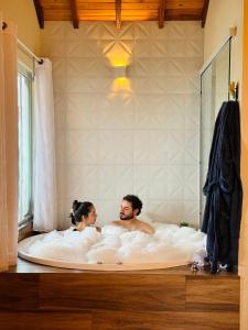 a man and woman sitting in a bath tub at Chalés Vila do Moinho in Monte Verde