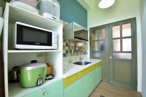 a small kitchen with a sink and a microwave at Mary B&B瑪莉年代-親子友善 租車優惠 近火車站 可包棟 電動麻將 BBQ KTV in Taitung City