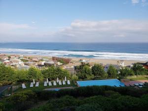a beach with a group of umbrellas and the ocean at Departamento en Cachagua con vista al mar y piscin in La Laguna Zapallar