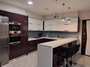 a kitchen with white cabinets and a counter with chairs at Double-V apartment in Pyrgos