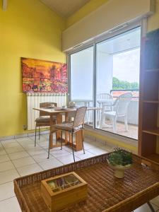 a living room with a table and chairs and a large window at L'Aurore - Terrasse - Duplex - Parking in Dax