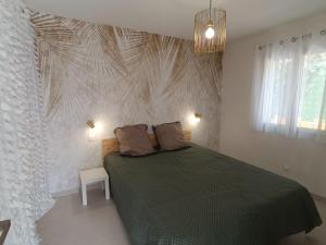 a bedroom with a green bed with a white wall at Maison T2 avec jacuzzi in Ensuès-la-Redonne