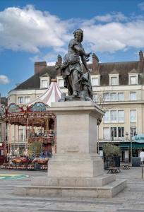 a statue of a man standing next to a carousel at Le Parfait in Beauvais