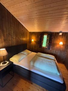 a large bed in a room with wooden walls at Cozy lakeside cabin in Buvika