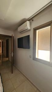 a room with a flat screen tv and a window at Bright and Cosy appartment in Oulad Yakoub