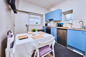 a kitchen with a white table and blue cabinets at Dunluce Green 1 - Portrush by the Sea in Portrush