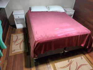 - une chambre avec un lit recouvert d'une couverture rose dans l'établissement Casa Villagio - CONDOMÍNIO, à Gramado