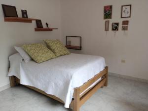 a bedroom with a bed with white sheets and pillows at Central, mejor clima, campestre en Calambeo, a 5 minutos de la vida cultural in Ibagué