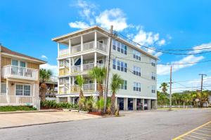 a white building with palm trees in front of a street at Oceanview on Tybee 202-2 in Tybee Island