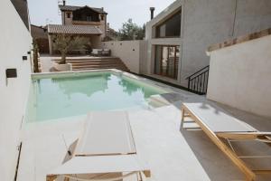 Una piscina con dos tumbonas y una casa. en La Toscana Casa Rural piscina ,parking ,barbacoa, en Jadraque