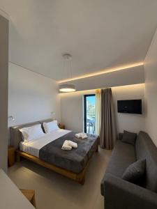 a bedroom with a bed and a couch at Thalassa Luxury Apartments Nea Styra in Nea Stira