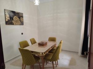 a dining room with a wooden table and green chairs at Cozy appartement in Tangier in Tangier