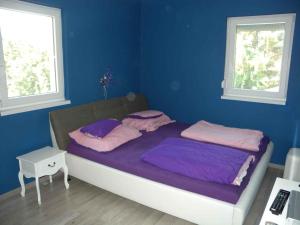 a bedroom with a bed with purple sheets and two windows at Apartment in Siofok - Balaton 34933 in Balatonszabadi Fürdőtelep +21 photos