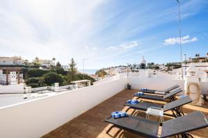 a balcony with chairs and tables on the roof of a house at Casa das Conchas in Carvoeiro