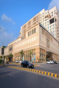 a black car parked in front of a large building at Luxurious One-Bedroom Gold Crest Apartment with Stunning Balcony Retreat DHA Lahore in Lahore
